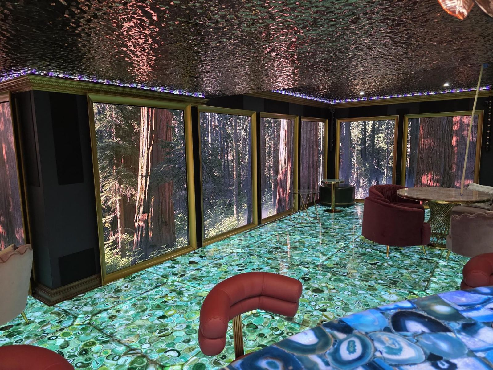 Lounge with LED wall forest scenes in gold frames over a backlit agate floor